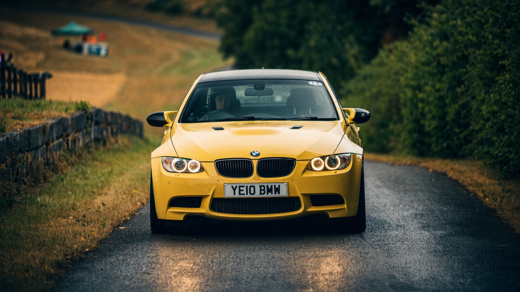 Chase Armitage driving a yellow BMW M3 on a wet country road