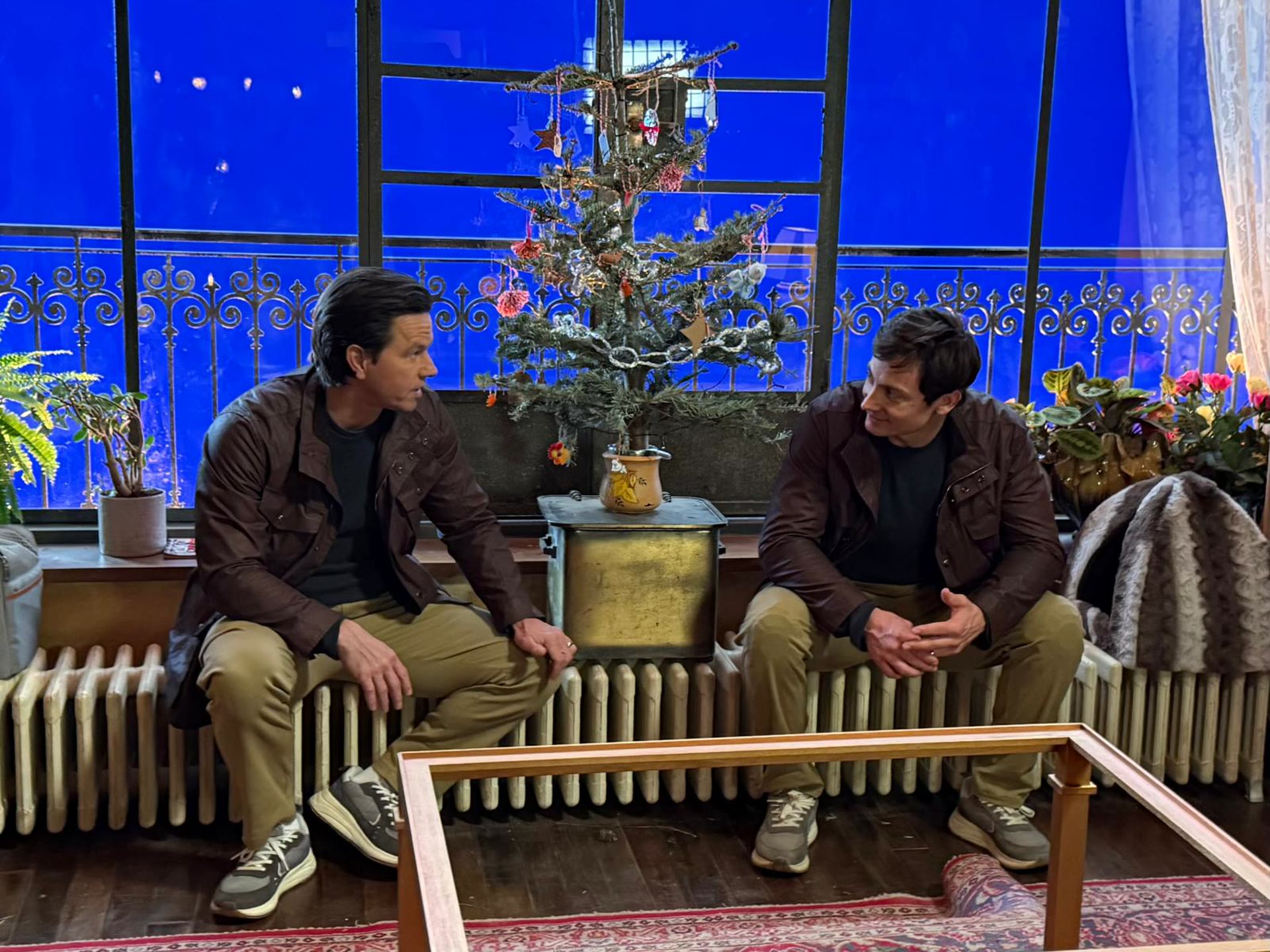Chase Armitage and Mark Wahlberg sitting together on the Family Plan 2 set in matching outfits